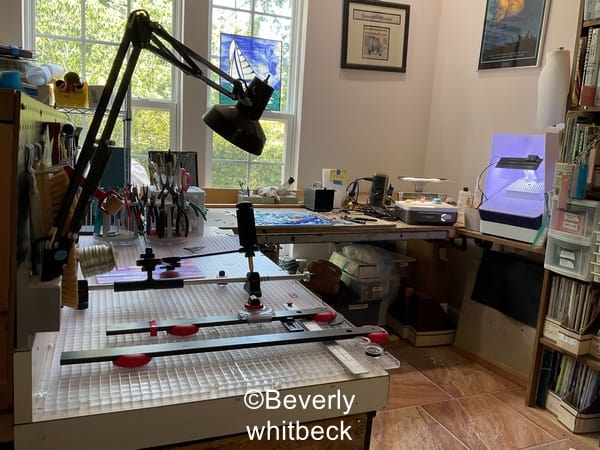 A picture of a stained glass studio adapted for a wheelchair user showing an L shaped desk and pegboard